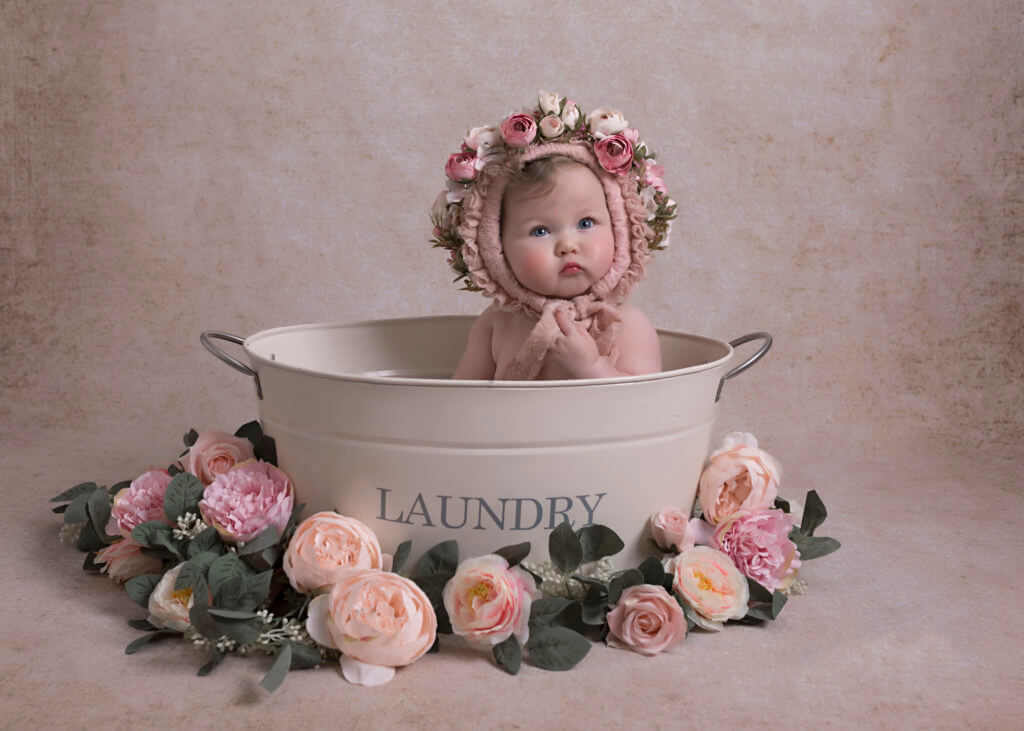 baby in a flower bonnet sat in bath tub Birmingham baby photographer