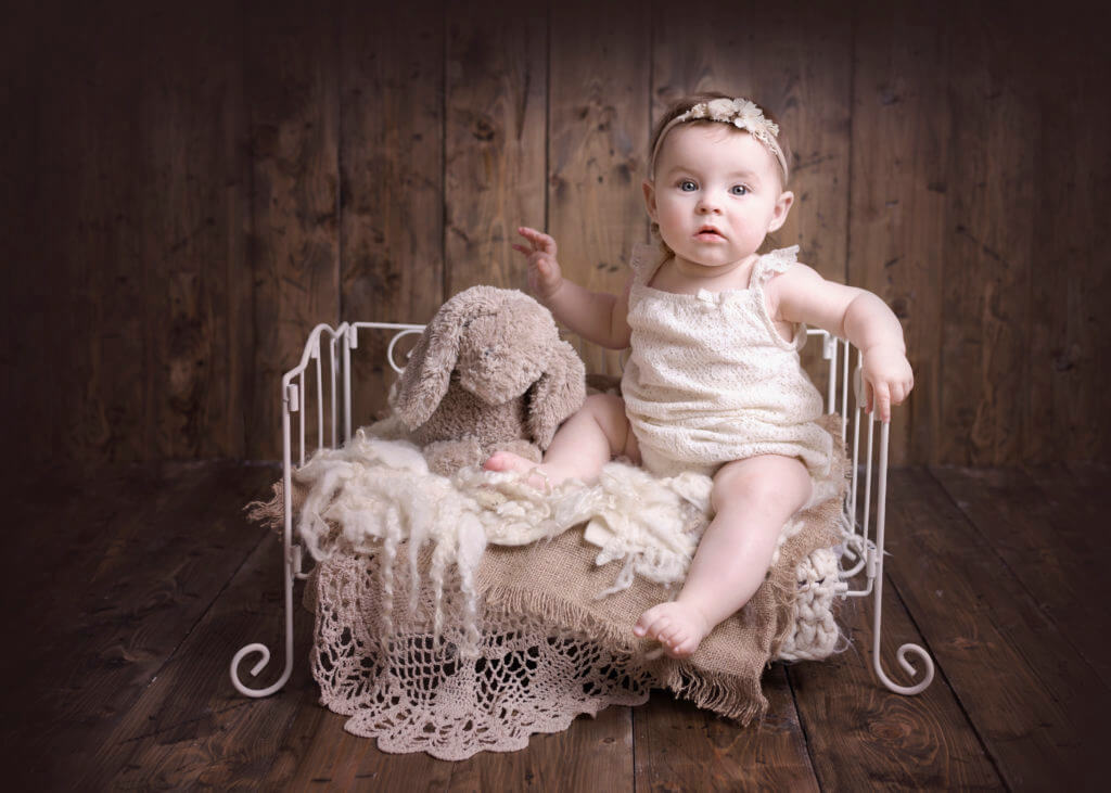 Gorgeous baby girl at her Birmingham based baby pho shoot sitting on a little vintage bed